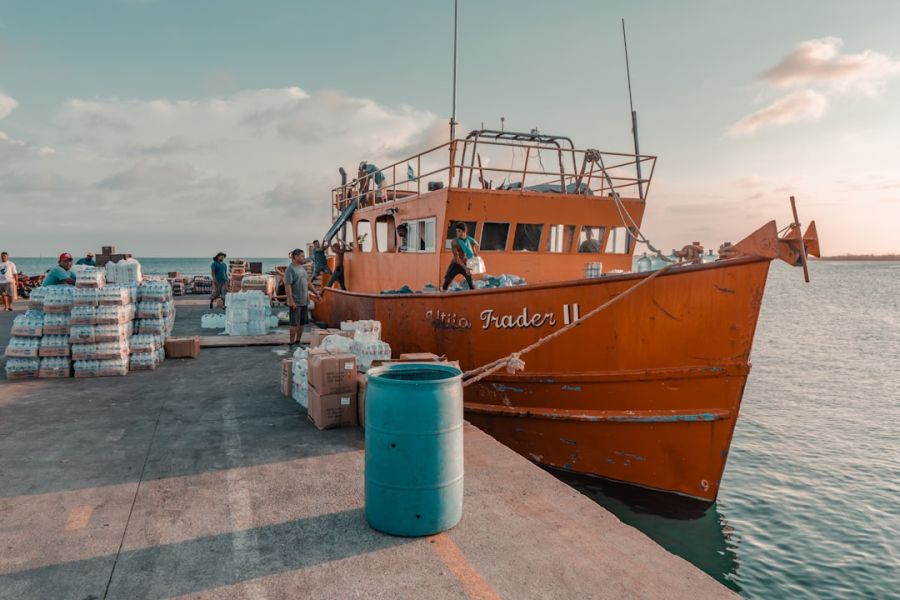 Workers loading supplies onto orange boat at dock