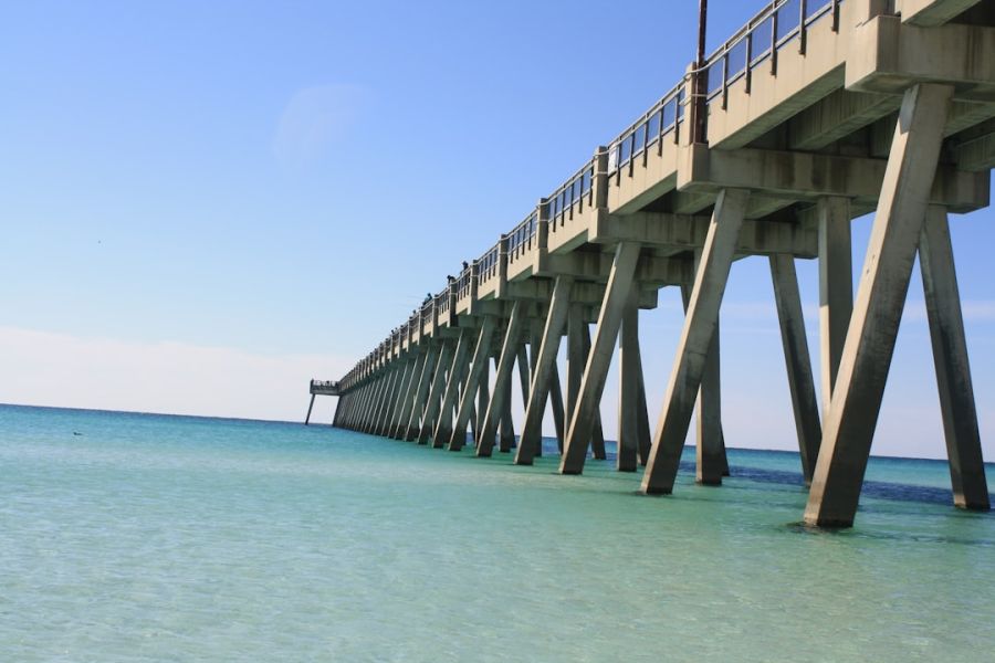 Pier extending over turquoise ocean to horizon.