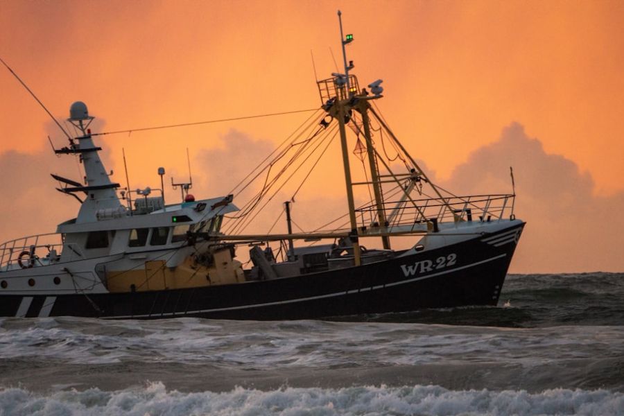 Fishing boat riding waves at sunset