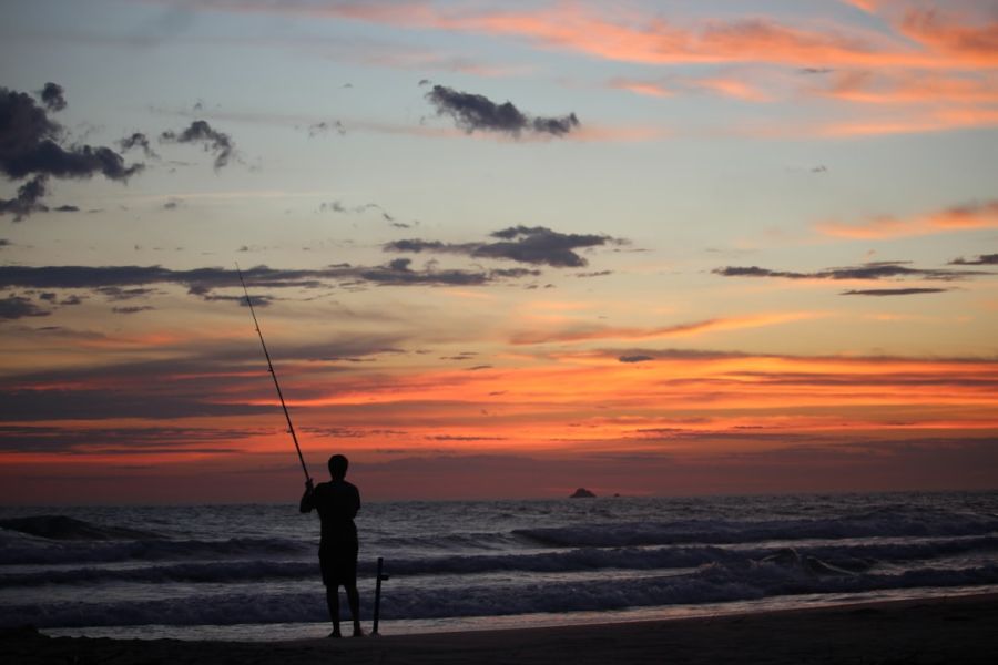 Silhouette of a person fishing at sunset