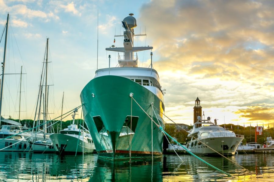 Green yacht moored at marina at sunset.