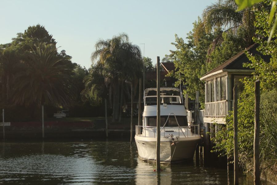 White yacht moored beside riverside house