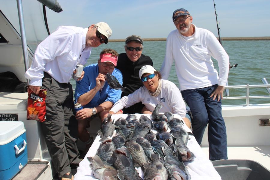 Five people posing with many fish on boat