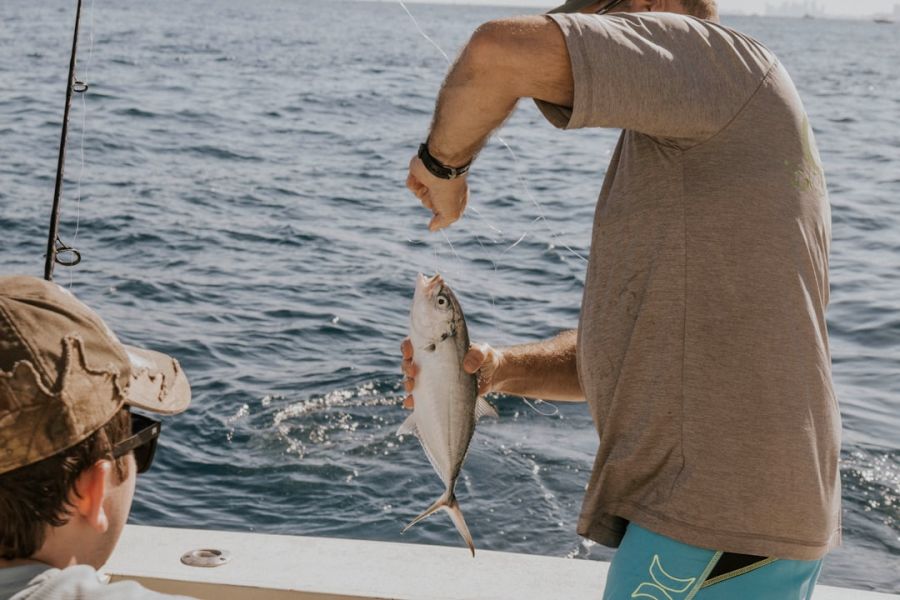 Fisherman on boat catching a small fish.