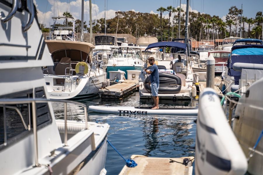 Man standing on paddleboard at marina.