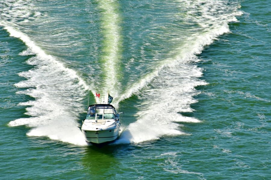 White speedboat creating wake in green water