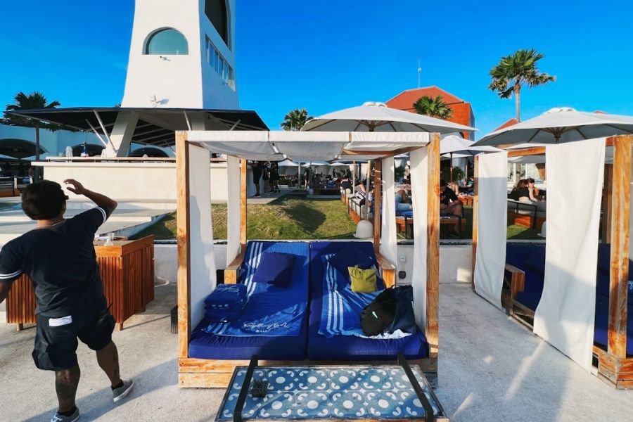Outdoor lounge cabanas with blue cushions and umbrellas.