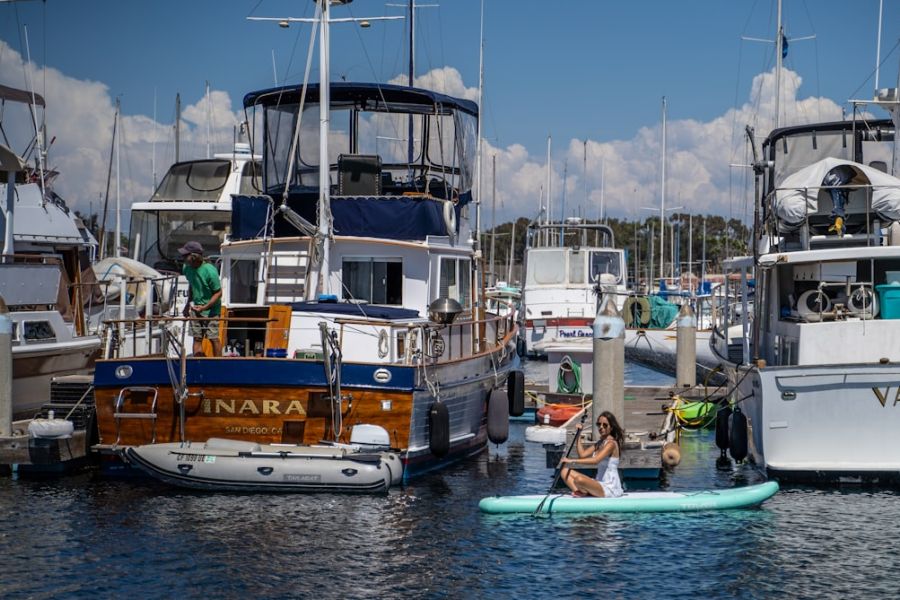 Woman paddling on paddleboard beside yachts.