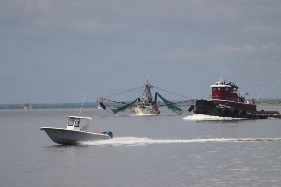 Small motorboat near fishing vessel and tugboat