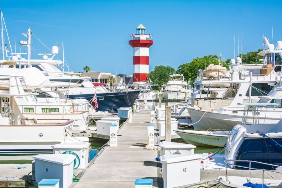 Boats docked at marina with striped lighthouse.