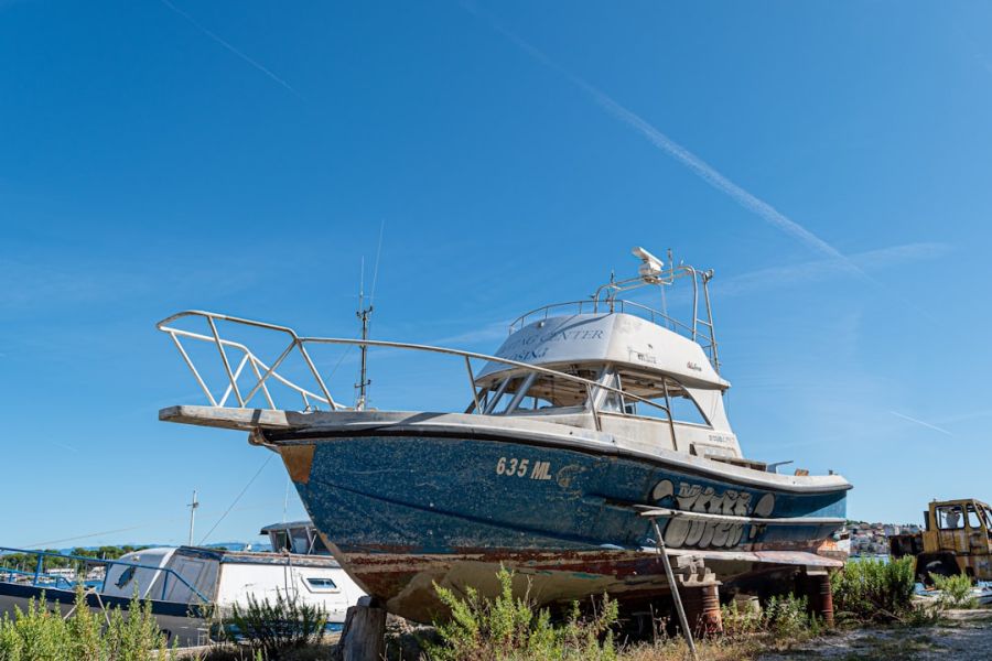 Old blue boat grounded on land.