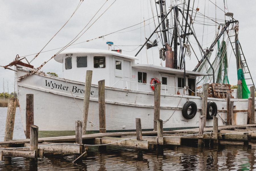 White fishing boat docked at weathered pier.