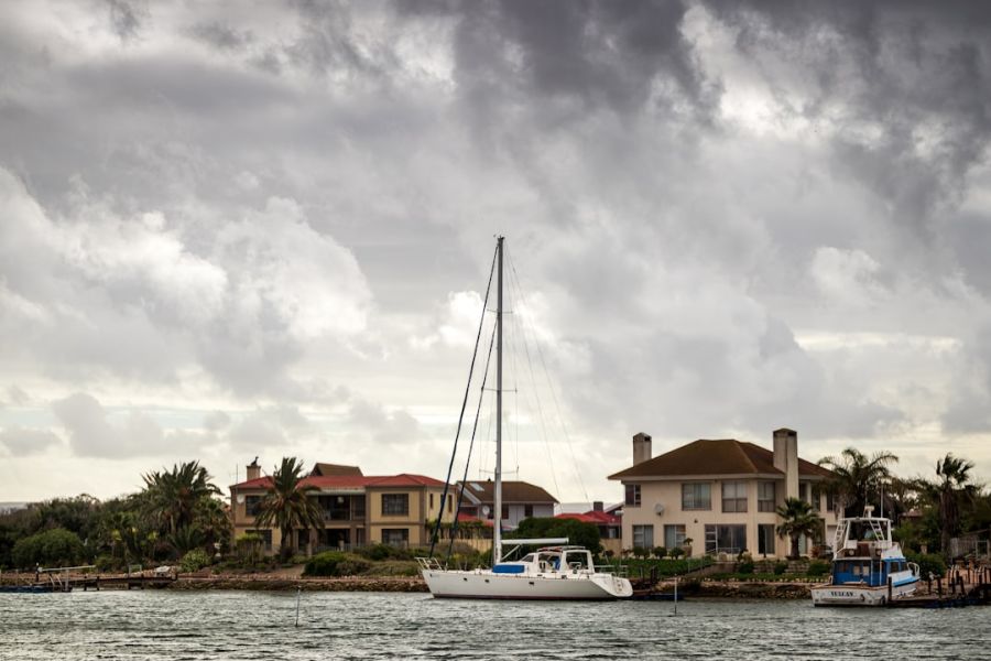 Sailboat anchored by waterfront houses.