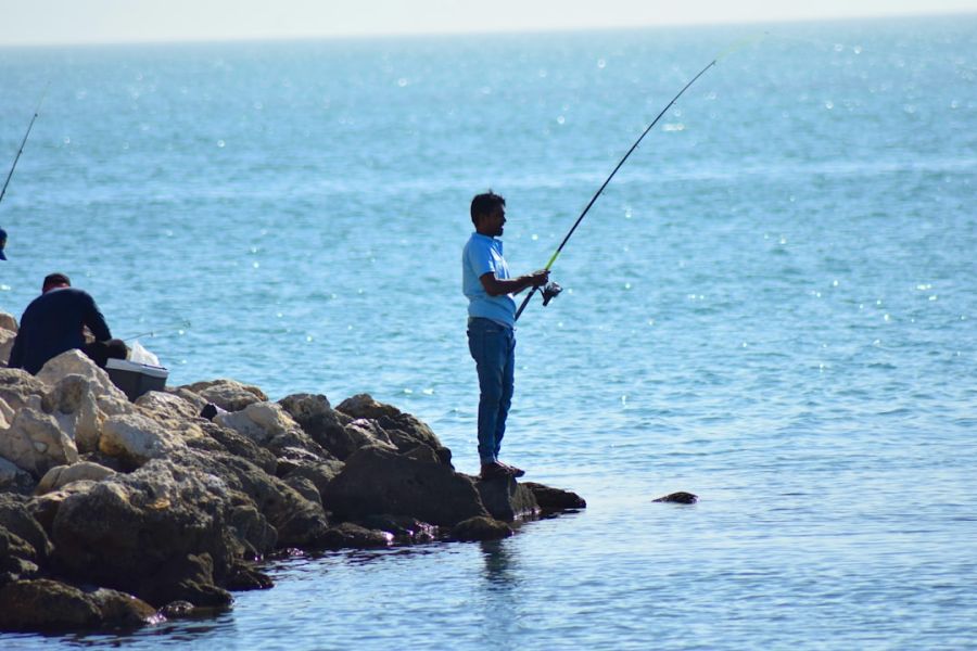 Man fishing on rocky shoreline by sea