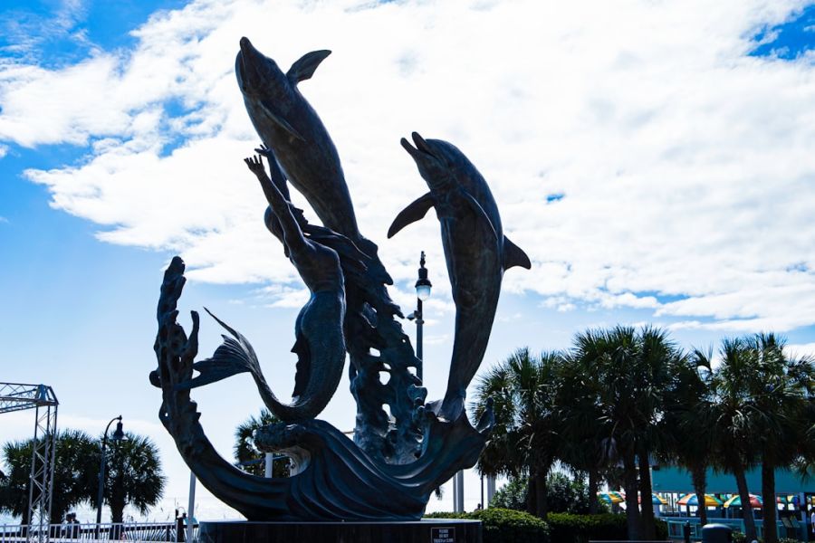 Leaping dolphins sculpture by waterfront palms