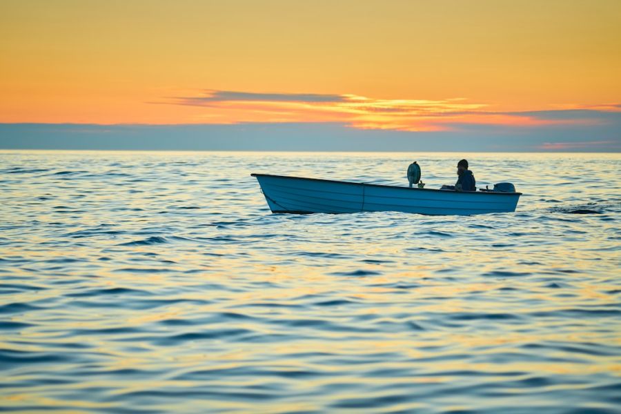 Small fishing boat with two people at sunset